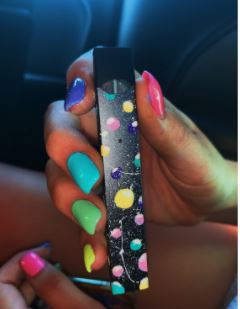 A JUUL  is painted and featured on the popular site VSCO. The JUUL seems to be painted the same colors to match the nails of the person holding it, overall matching the aesthetic of vaping in teens, and is just another way for vaping to appeal to high schoolers. Picture found on VSCO.
