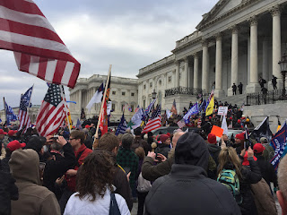 Capitol Conflict - Protestors waving American flags and posters supporting Donald Trump attempting to breach the capitol building during the January 6th Capitol riot. This riot calls into question the stability of the American political climate. 
