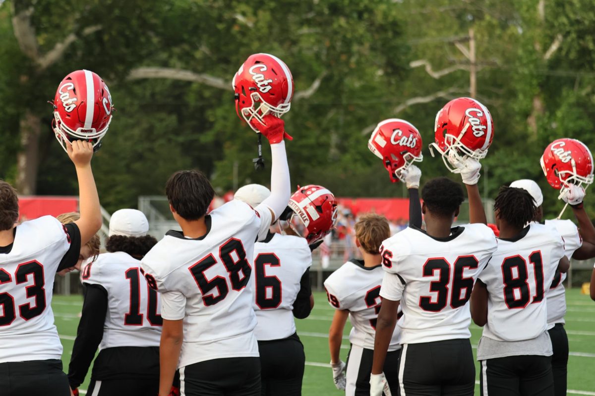 The football team doing the weekly tradition of holding their helmets up before the first kickoff of the game v.s. St. Charles.